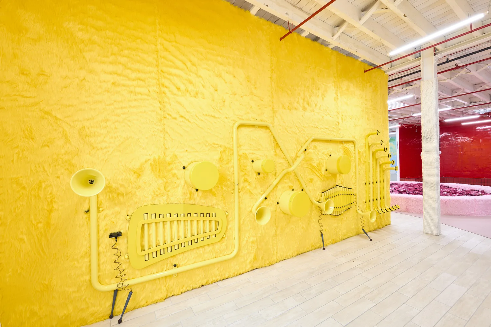 A yellow tactile wall fitted with air-powered tubes and play fixtures at Space Club DUMBO