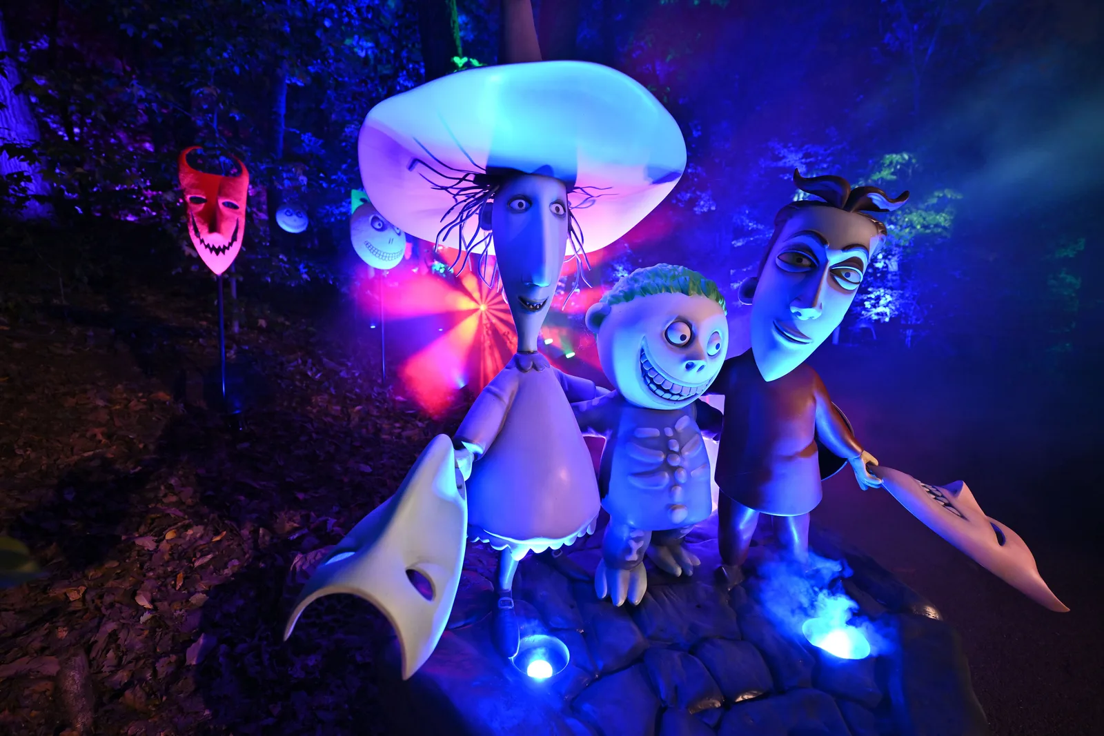 Illuminated figures from Halloween Town appear among trees at the New York Botanical Garden