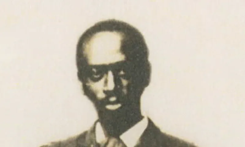 A sepia-toned portrait of a man dressed in a suit and a tie, looking directly at the camera.