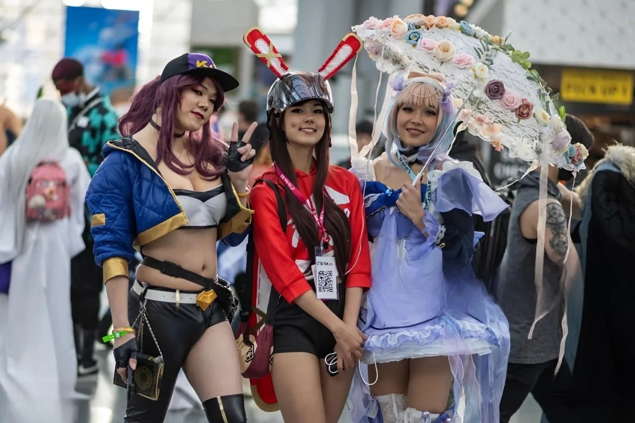Three Anime NYC attendees pose in detailed character costumes inside the Javits Center