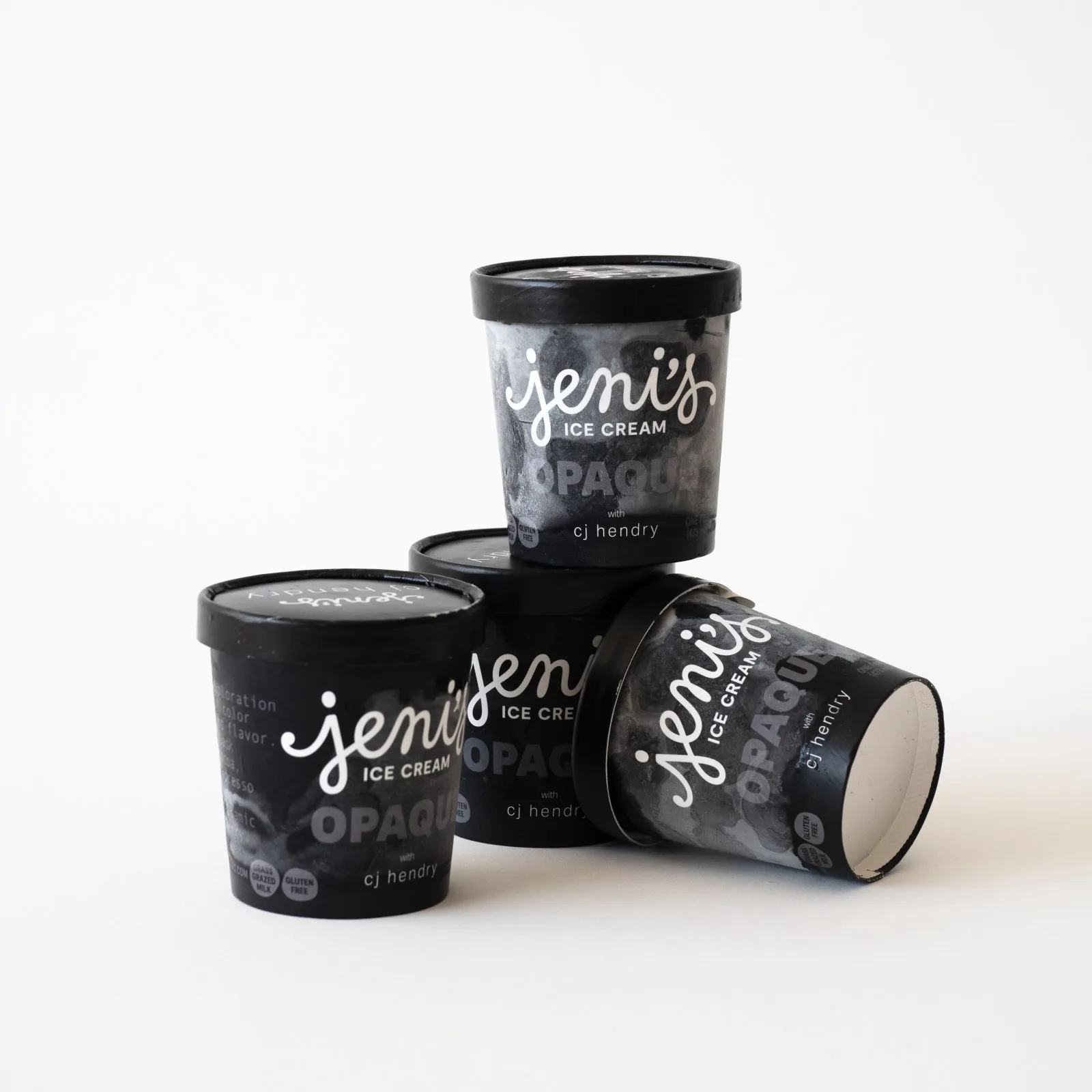 Four black Jeni's OPAQUE ice cream containers are arranged against a white background