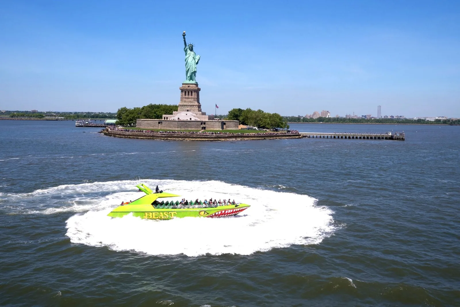 The bright green BEAST speedboat circles in front of the Statue of Liberty