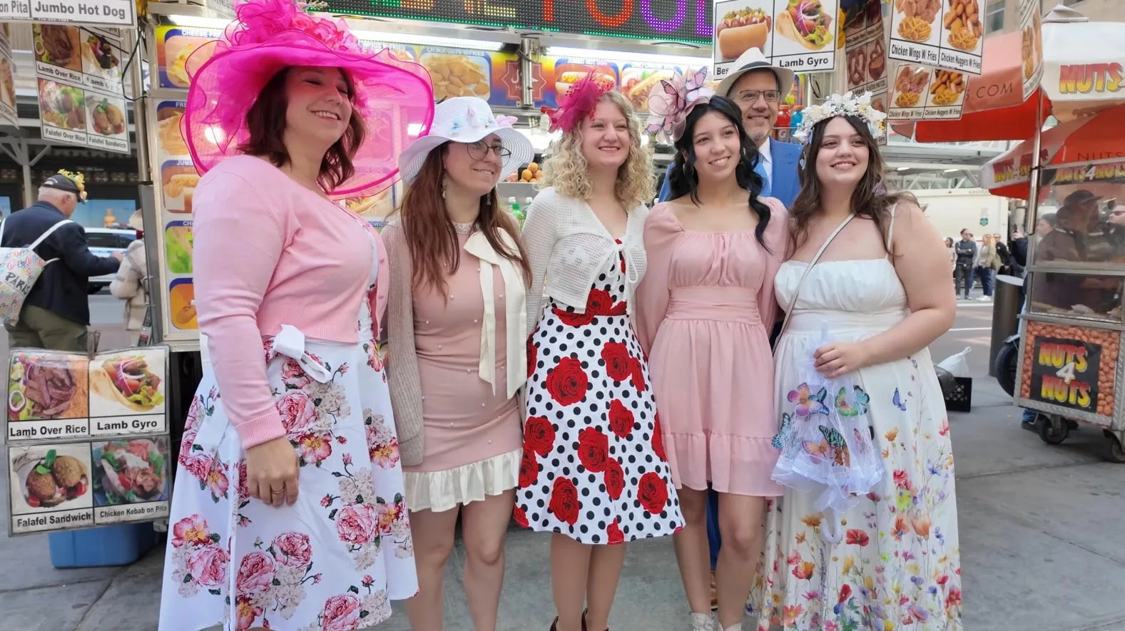 Festival participants in spring dresses and decorative hats pose on Fifth Avenue