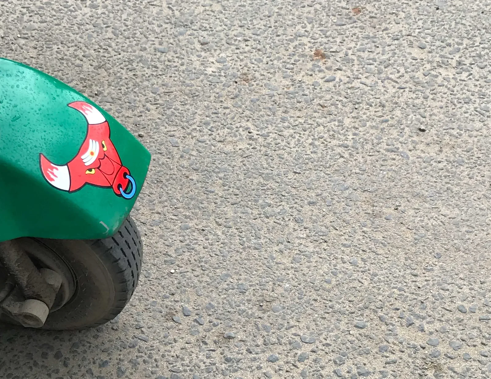 A sticker of a cartoon bull on the back of a green vehicle.