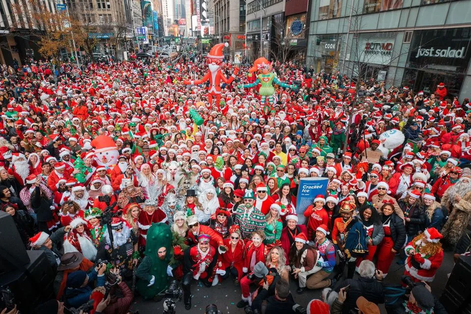Thousands of people in Santa suits and holiday costumes fill a Midtown Manhattan street
