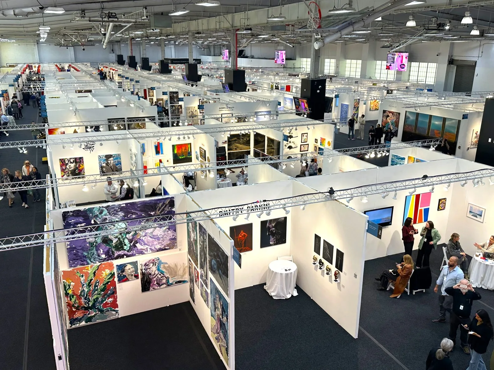 An elevated view across rows of art-fair booths inside Pier 36