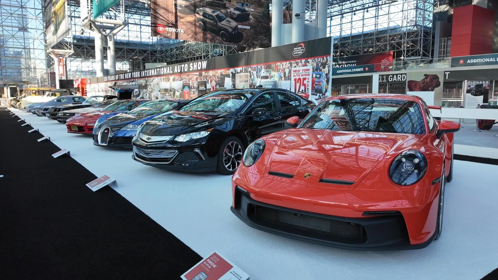 A row of historic sports cars led by a red Porsche at the Javits Center