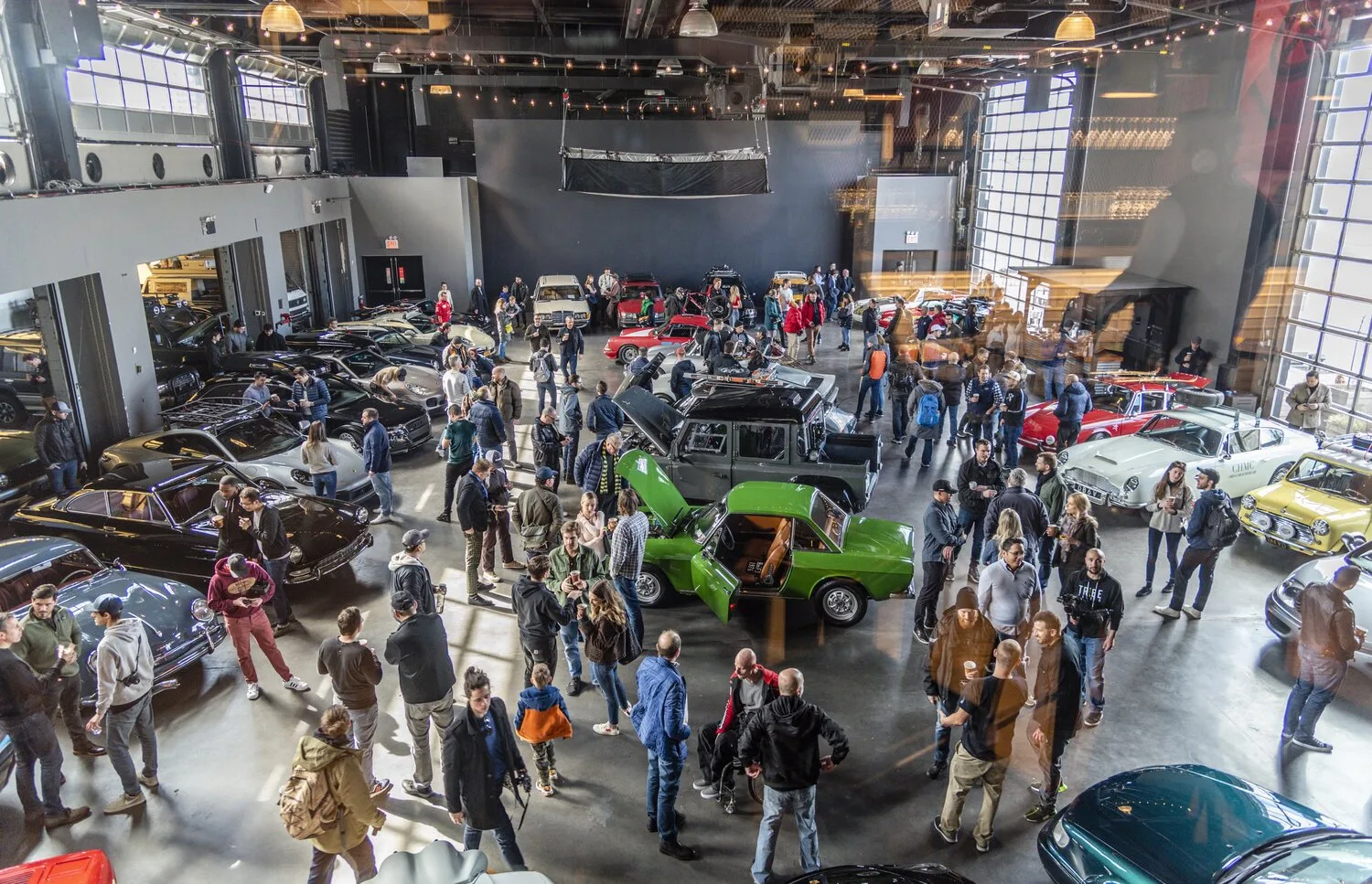 Visitors walk among classic and modern cars displayed inside a large event hall