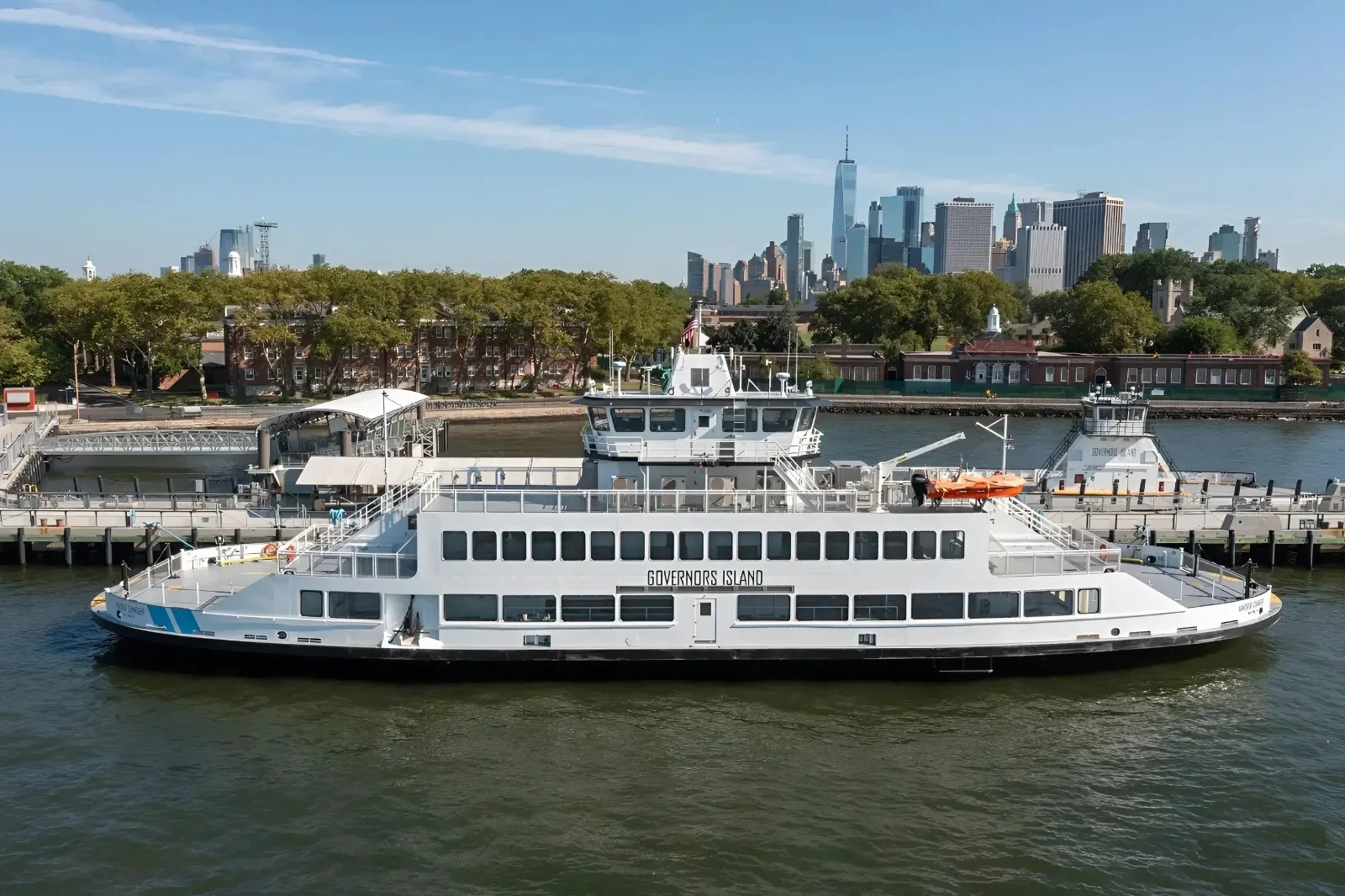 The white Harbor Charger ferry sits beside Governors Island with Lower Manhattan behind it