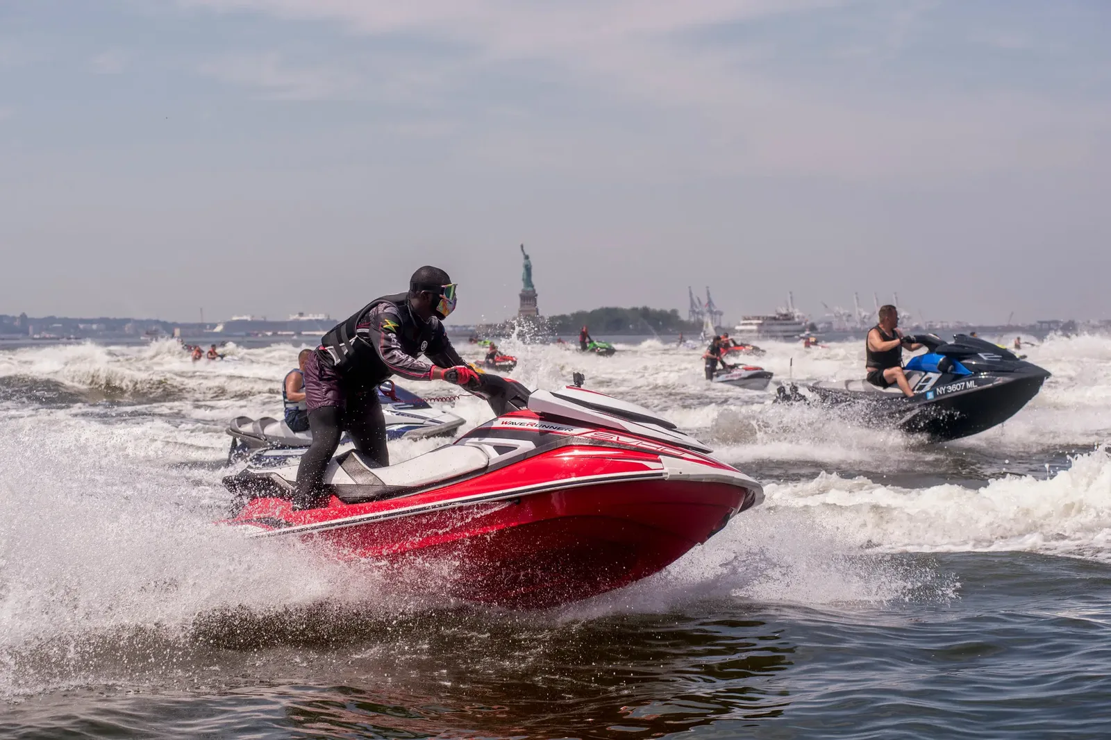 Personal watercraft cross New York Harbor with the Statue of Liberty in the distance