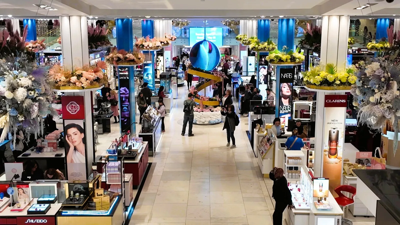 Floral platforms and a blue sculptural centerpiece run through the cosmetics department