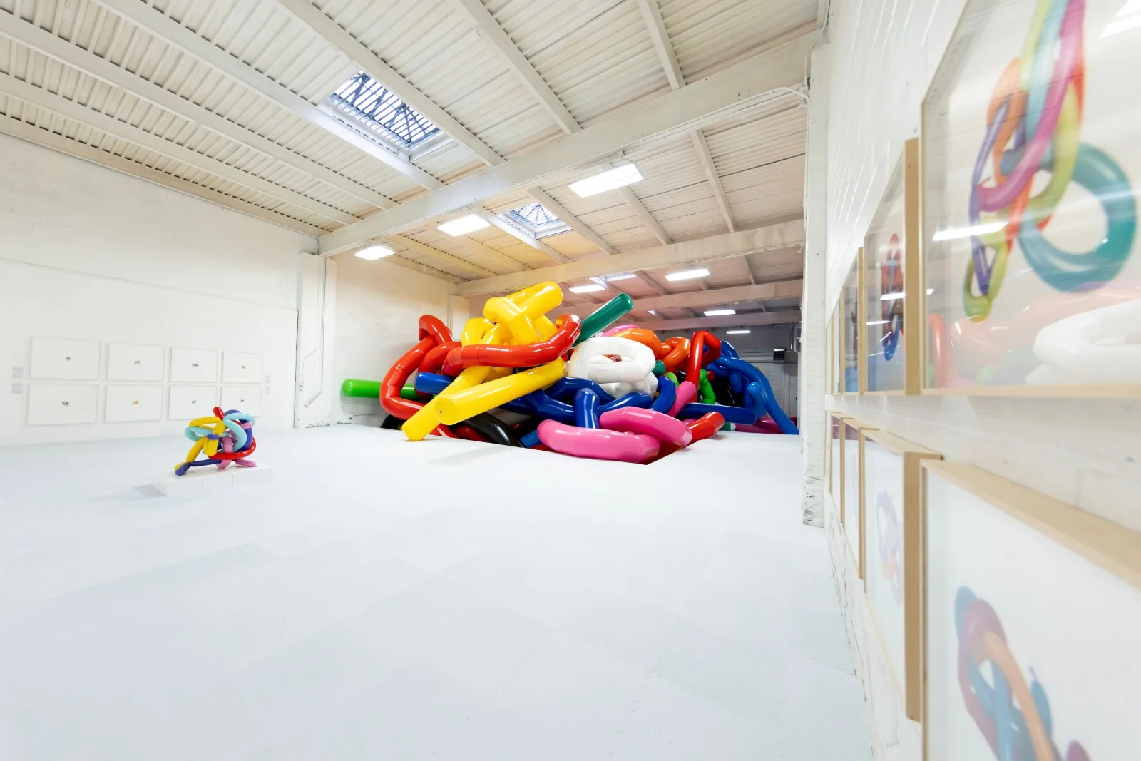 A monumental pile of glossy multicolored balloon-like knots fills a white gallery