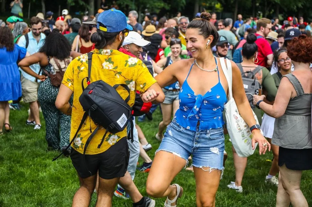 Two participants dance among a crowd wearing headphones in Hudson River Park