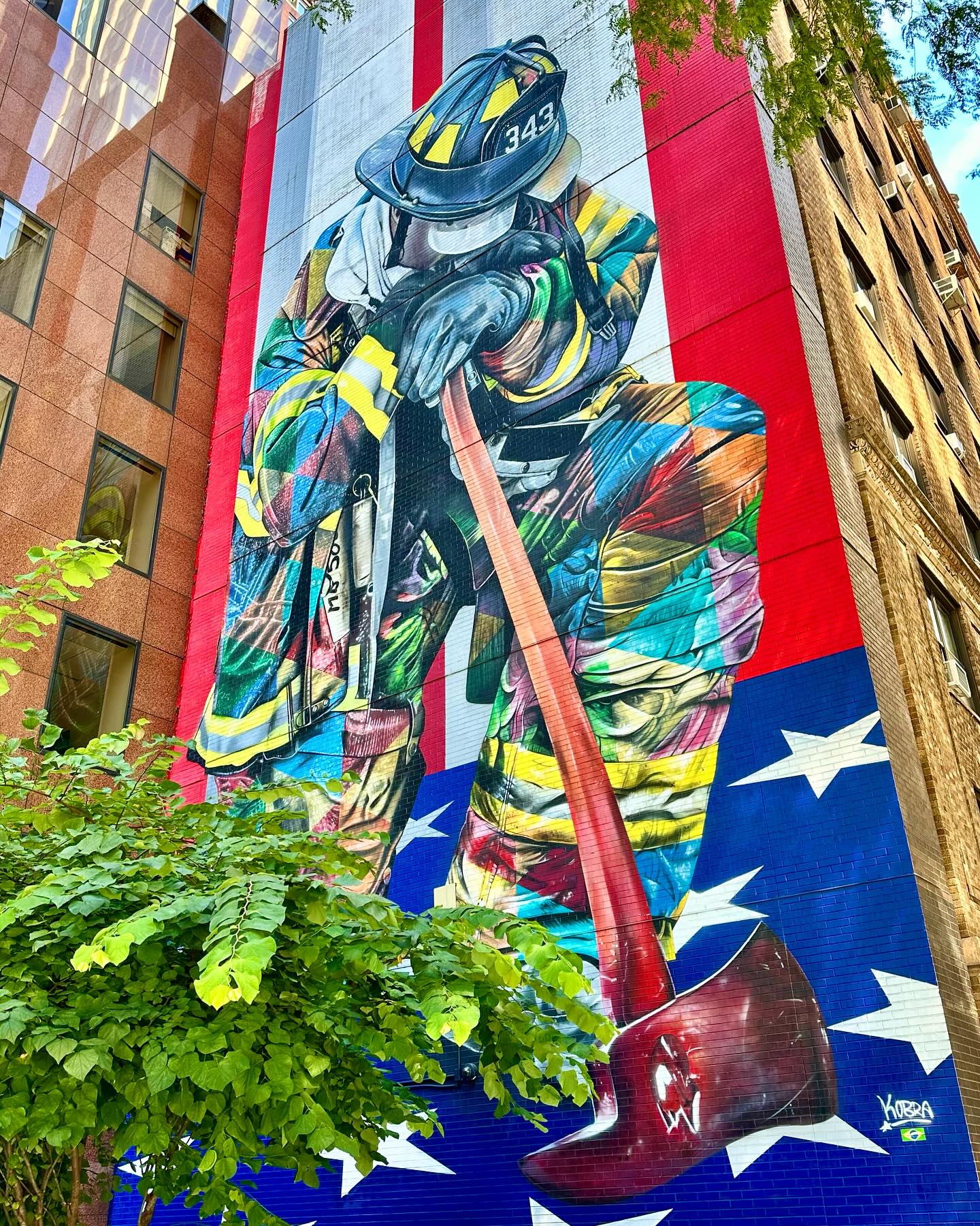 “The Braves of 9/11” by Brazilian street artist Eduardo Kobra. A seven-story mural depicts a firefighter kneeling in front of an American flag, symbolizing the bravery and sacrifice of the firefighters who responded to the 9/11 attacks. The number 343 on the firefighter’s helmet, representing the nu