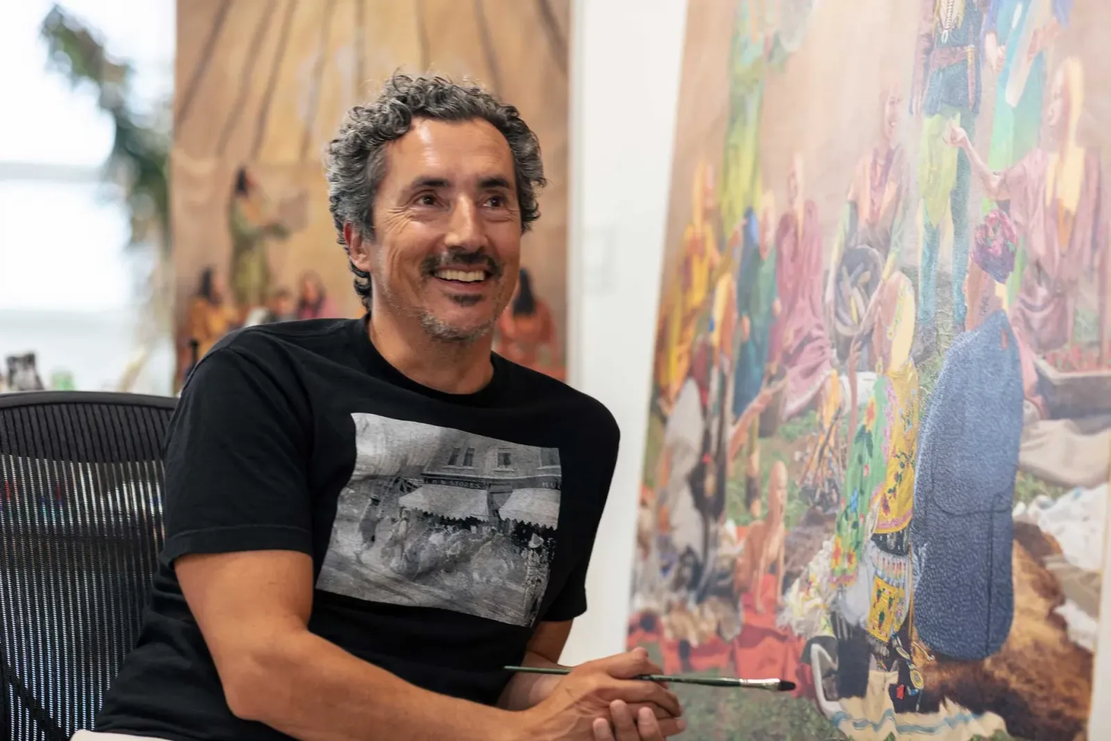 photo of Kent Monkman leaning near painting