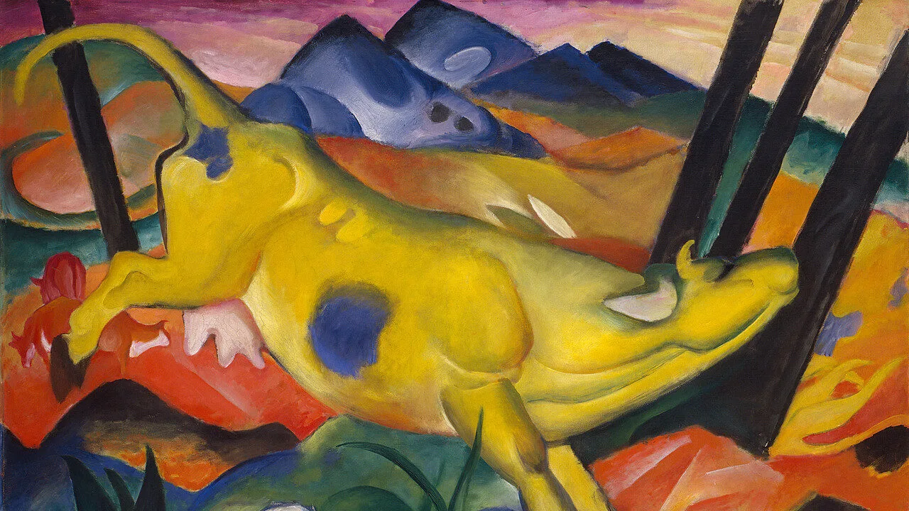 Oil painting by Franz Marc featuring a vibrantly colored abstract mountainous landscape with simplified figures of plants and wildlife in the background. In the foreground, centered in the painting, a yellow cow with white horns, blue spots and closed eyes leaps forward, with its back legs and tail ascending up into the air, 1911.